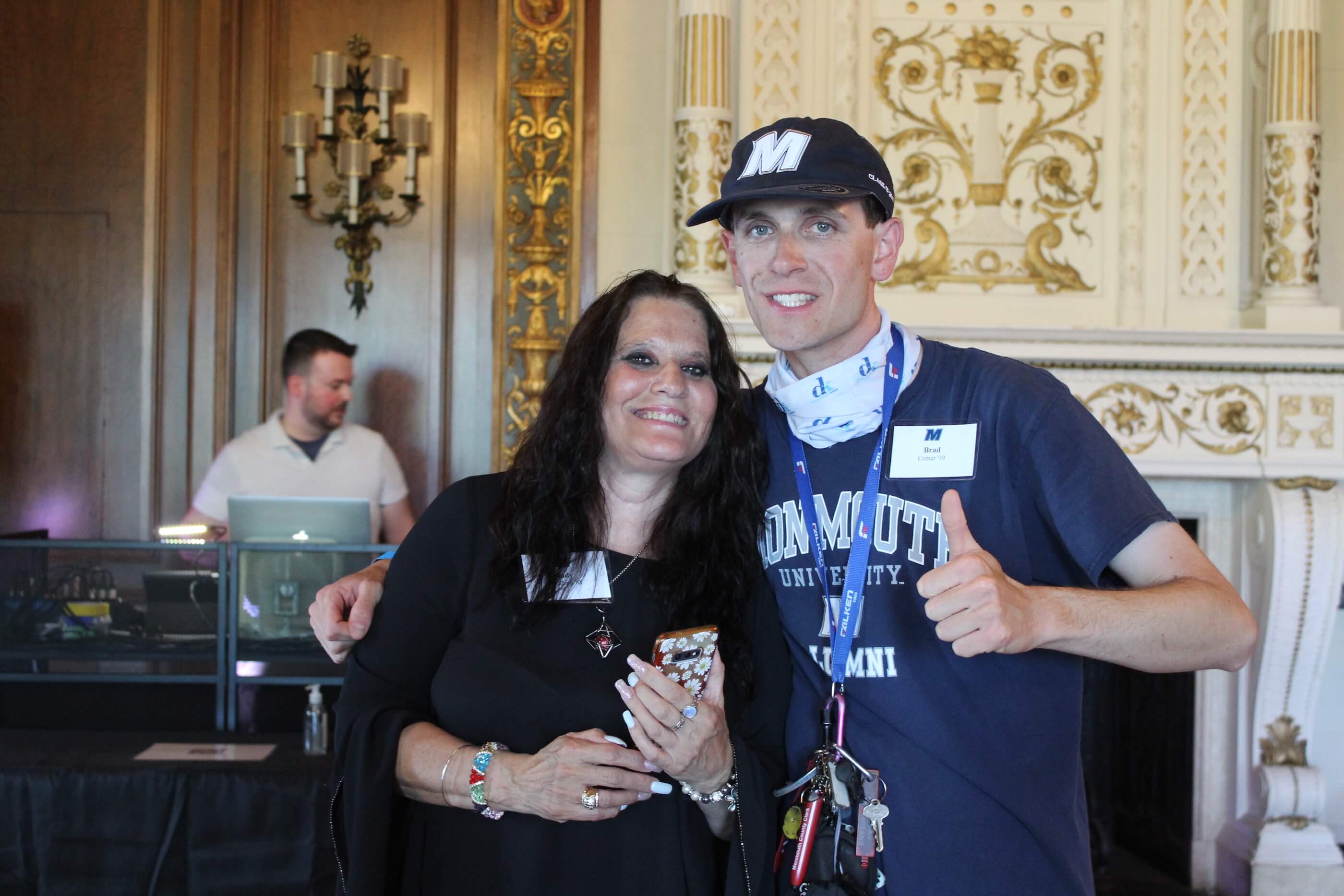 Man and woman smiling for camera in front of DJ in the Great Hall