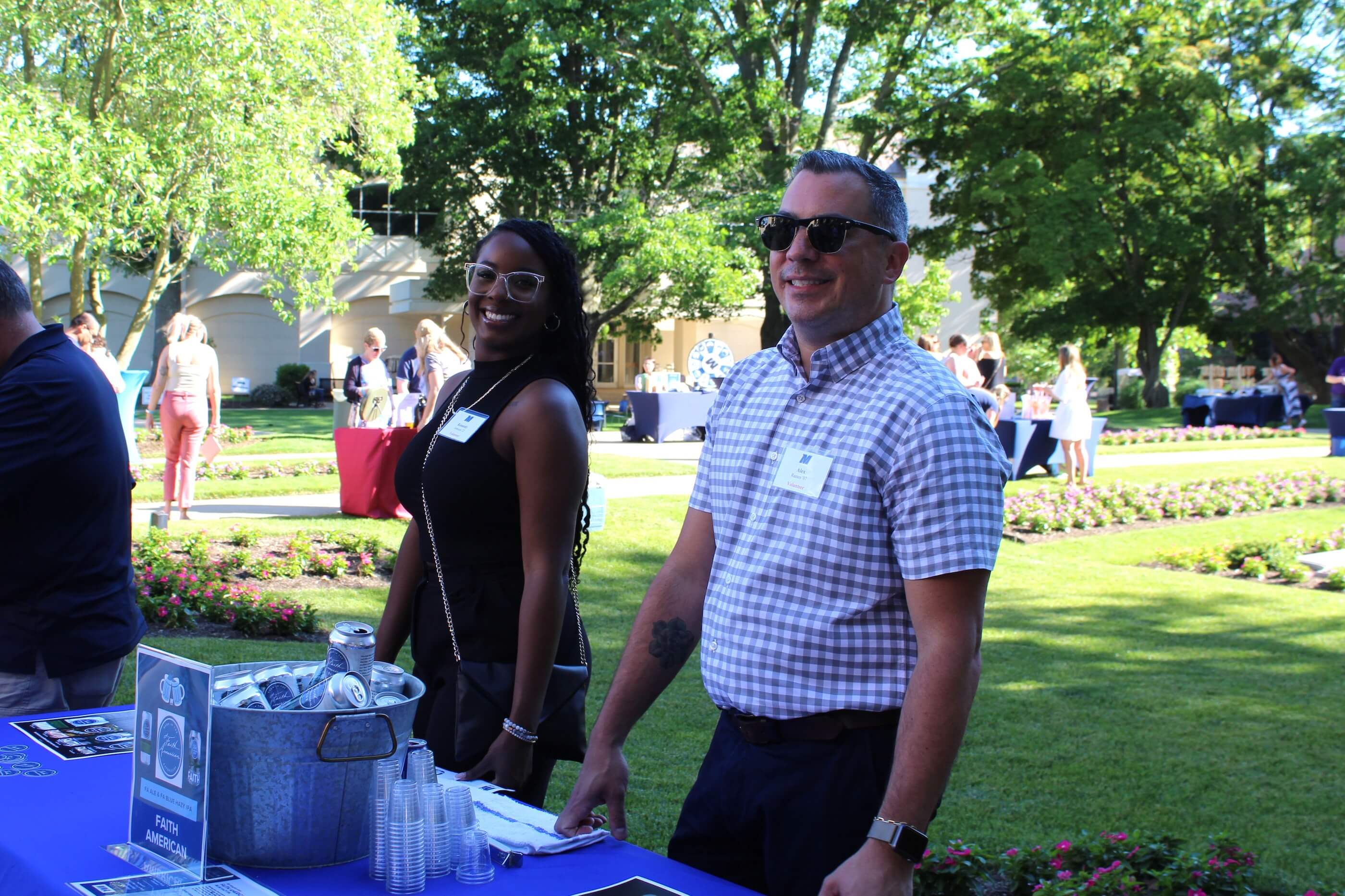 Two volunteers smiling at the Faith American Brewing Company table