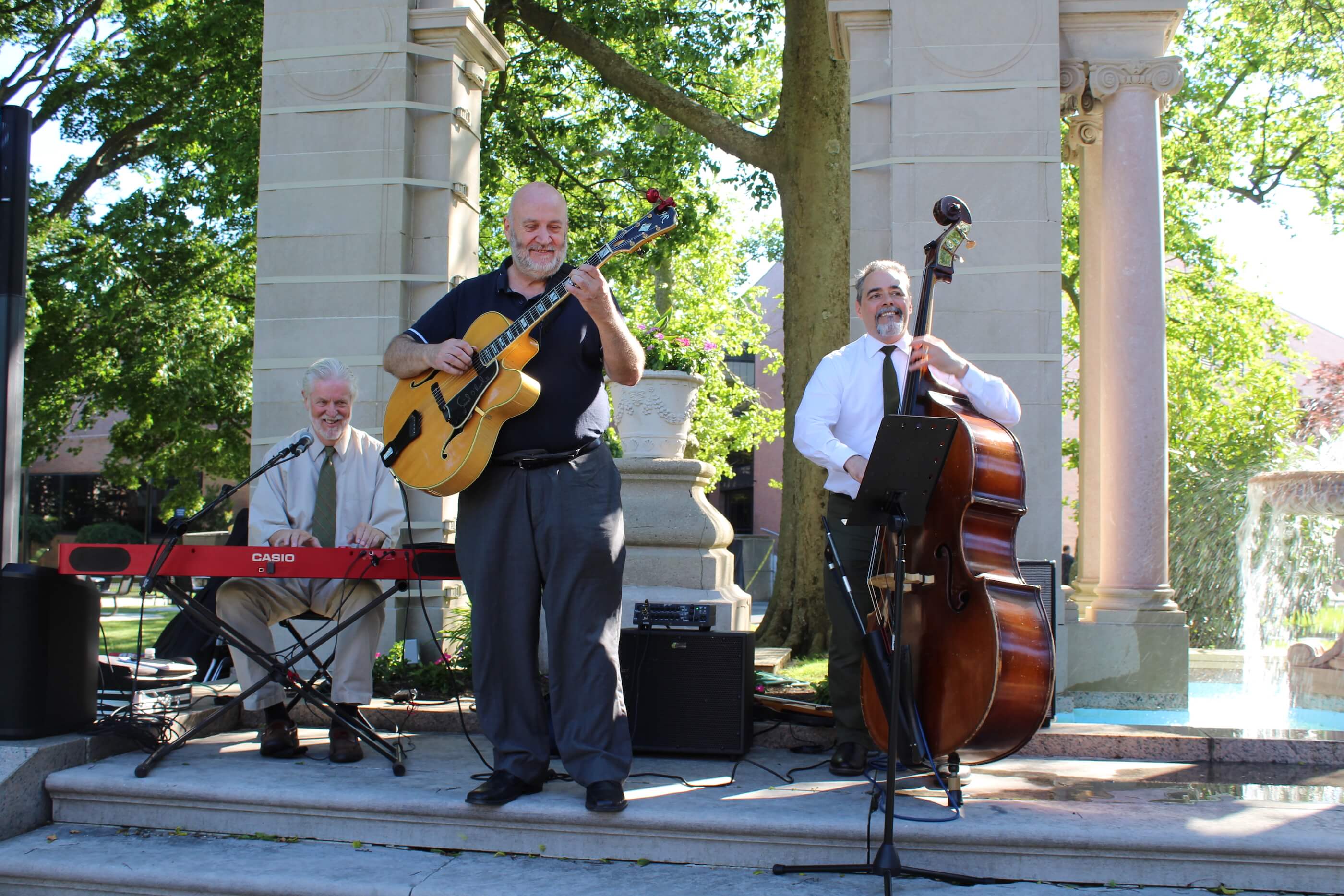 Keyboardist, guitarist, and cellist playing music by the fountains of Erlanger Gardens