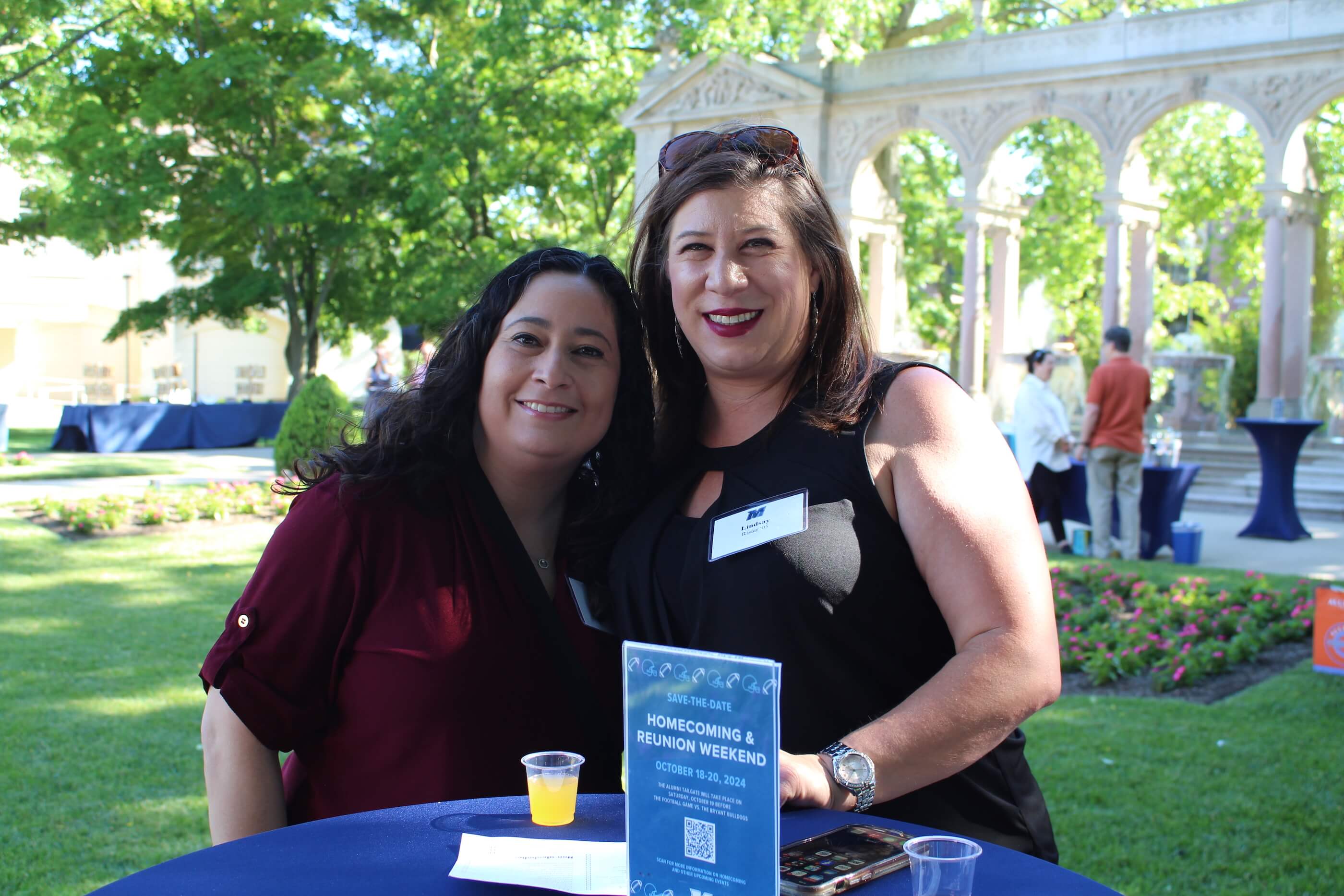 Two attendees smile for the camera together by table