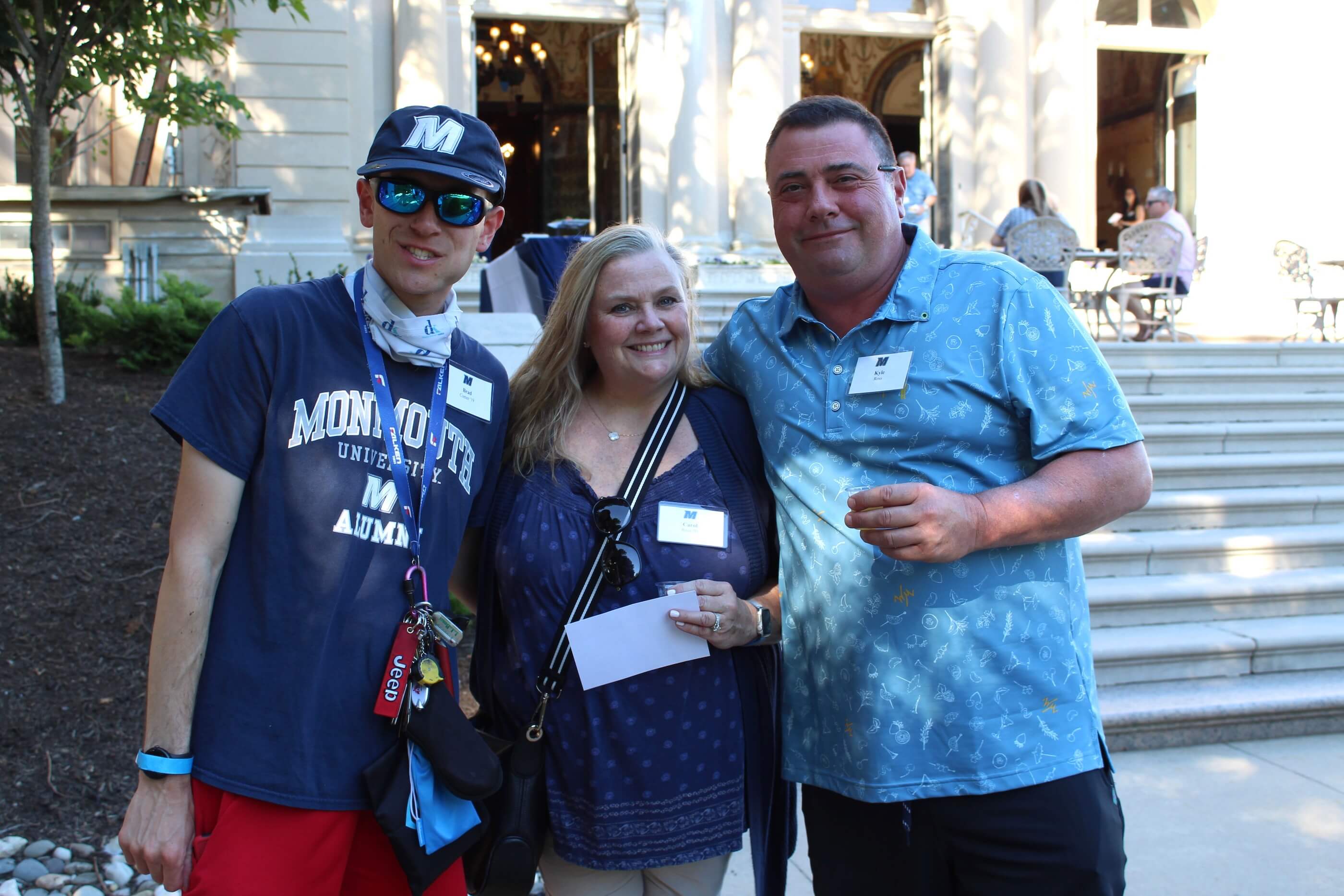 Three attendees pose for the camera by the steps of the Great Hall in Erlanger Gardens