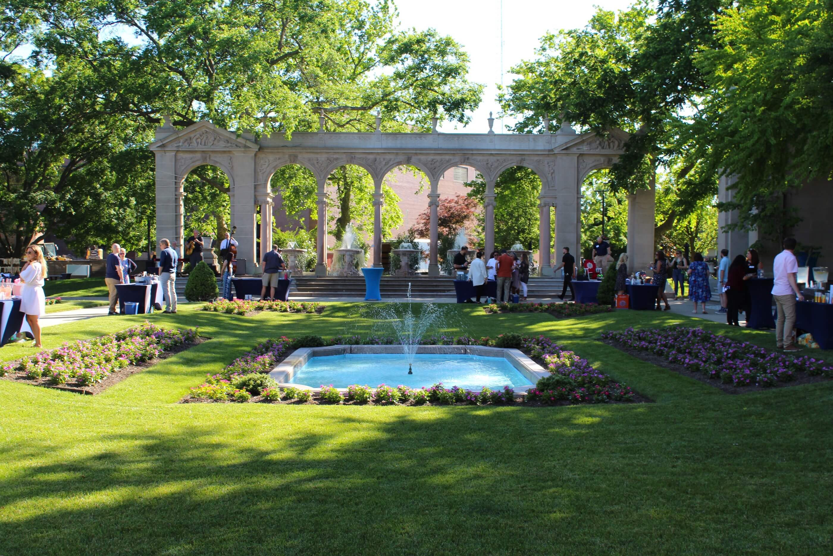 Shot of Wine vs Stein attendees enjoying themselves Erlanger Gardens, with the fountain on.