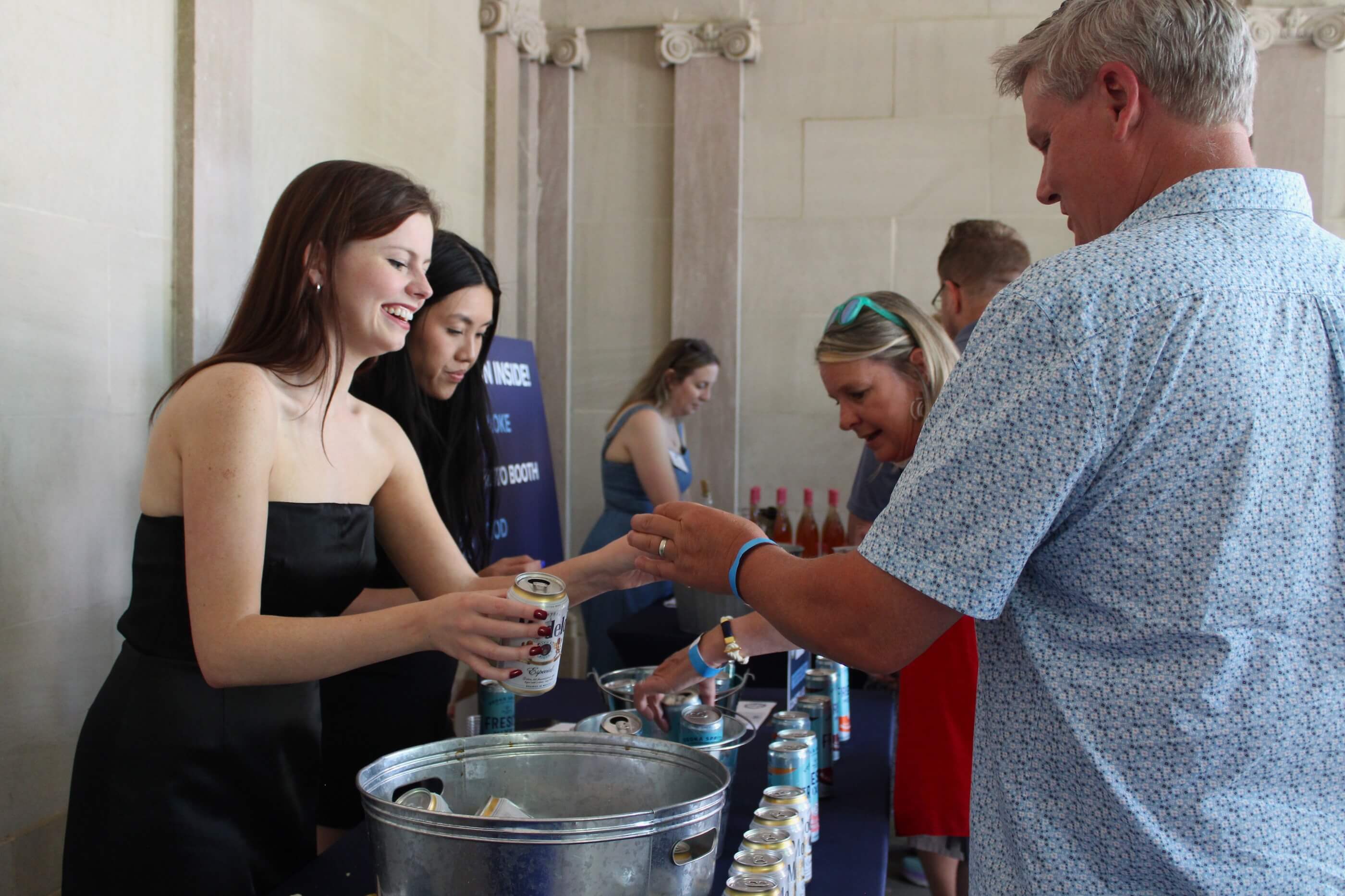 Woman gives man a sample of Modelo beer.