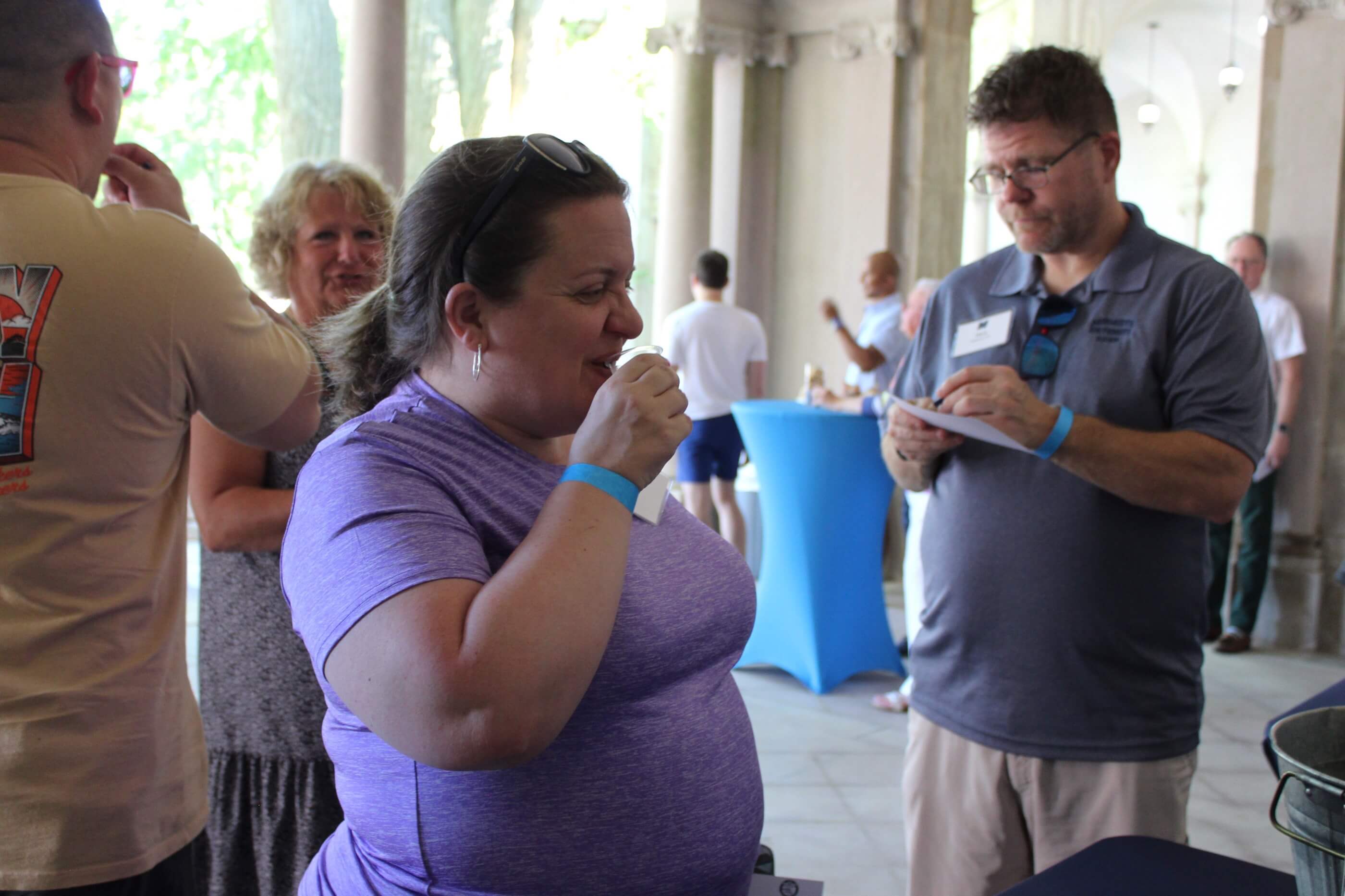 A woman sips from her tasting glass as other event goers enjoy themselves in Erlanger Garden