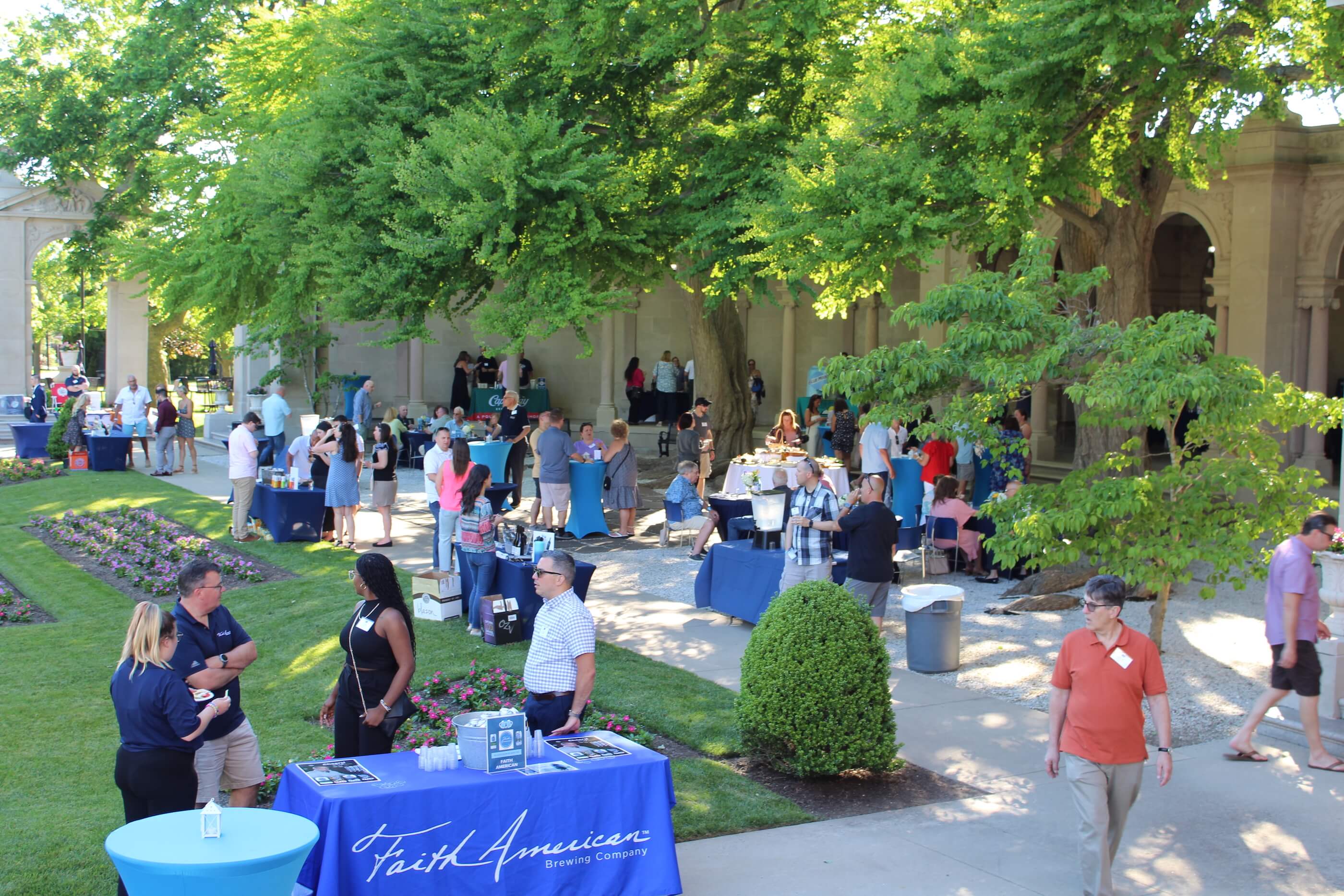 A shot of Erlanger Gardens with event goers talking among themselves, the various wine ane beer company tables visible