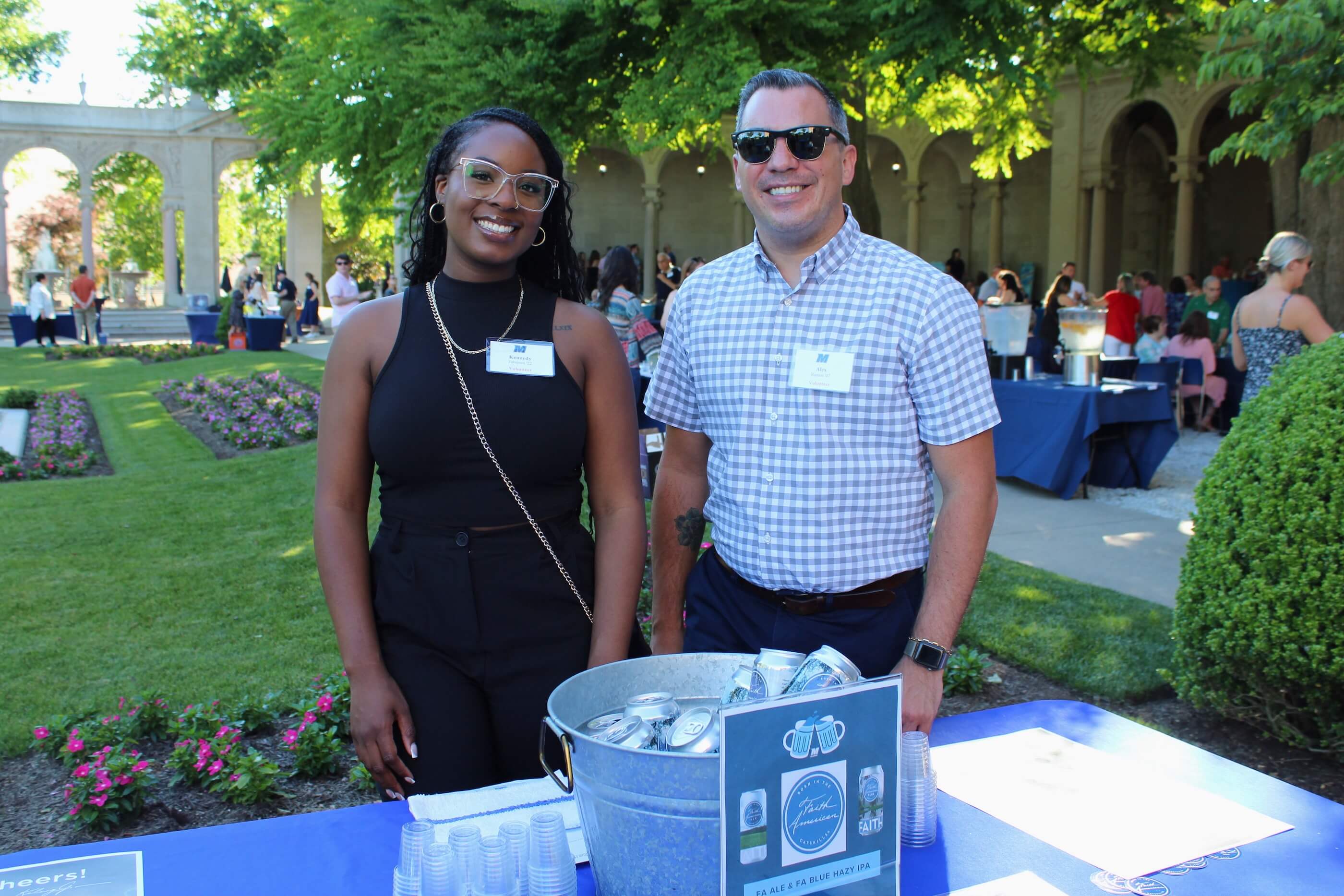 Two volunteers posing for a photo by the Faith American Brewing Company table at the Wine vs Stein event