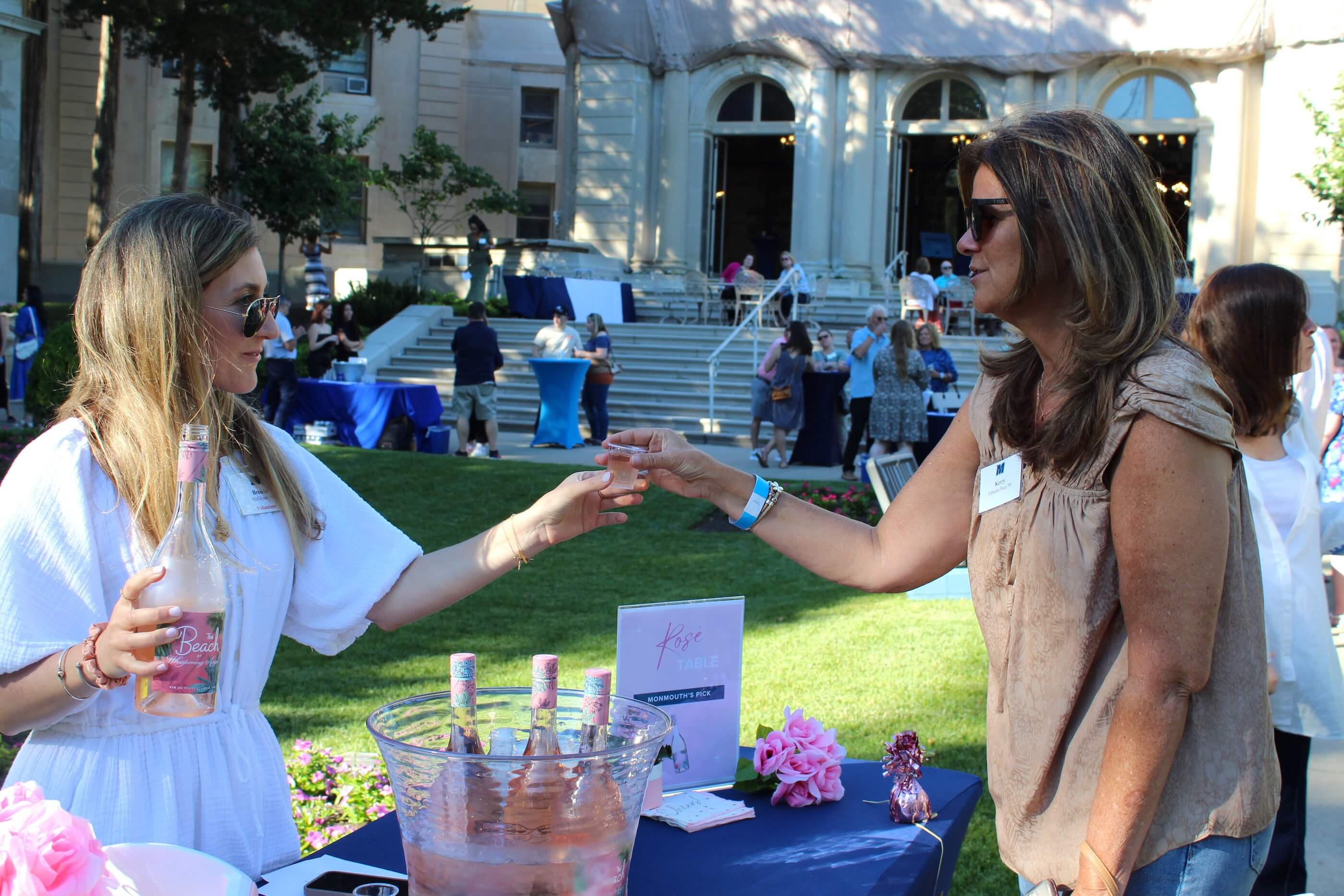 A volunteer hands an attendee a tasting glass with rosé