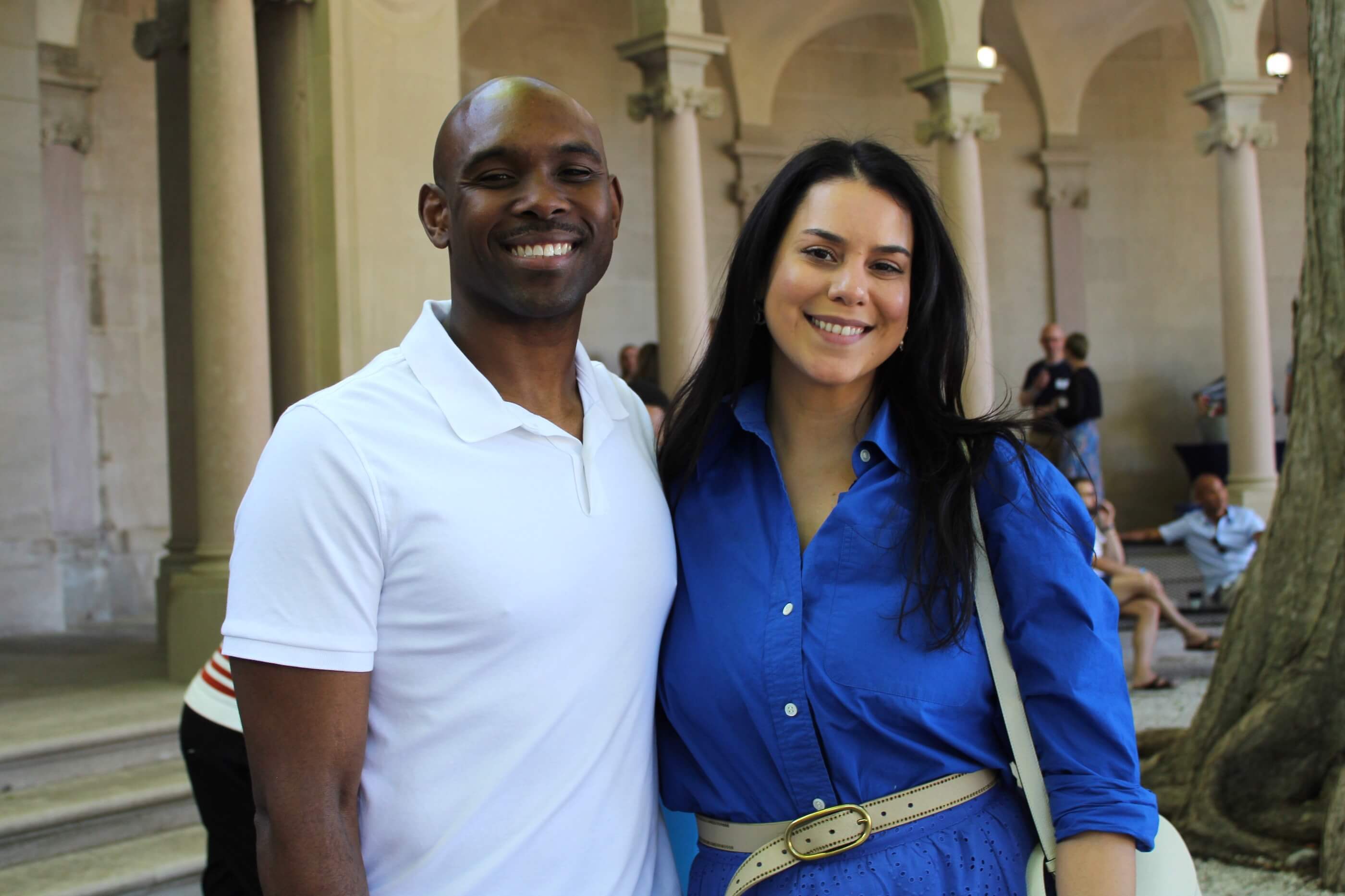 Two attendees smiling together for the camera, the columns of Erlanger Garden behind them