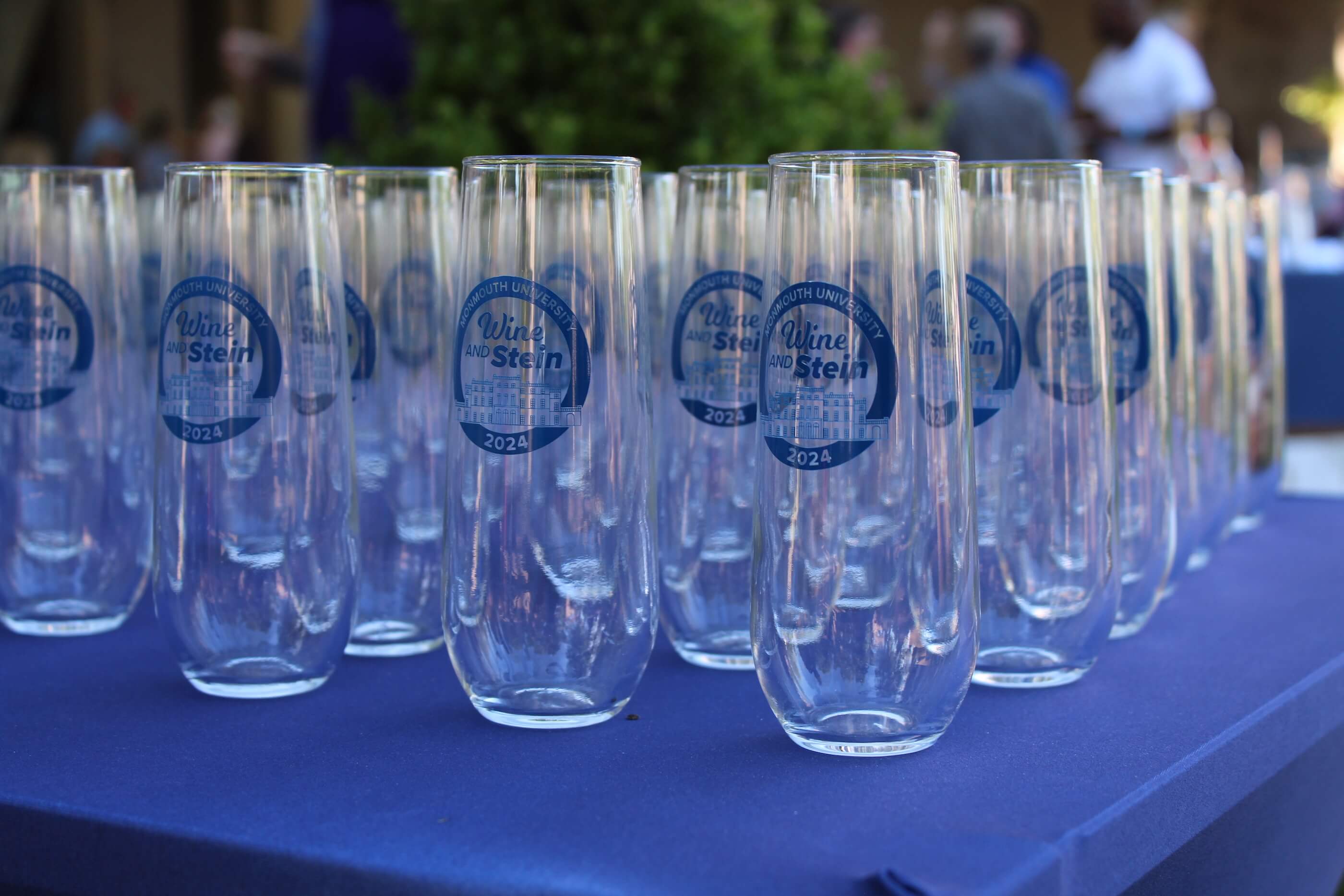 A table with drinking glasses, each featuring the logo for the Wine vs Stein 2024 event