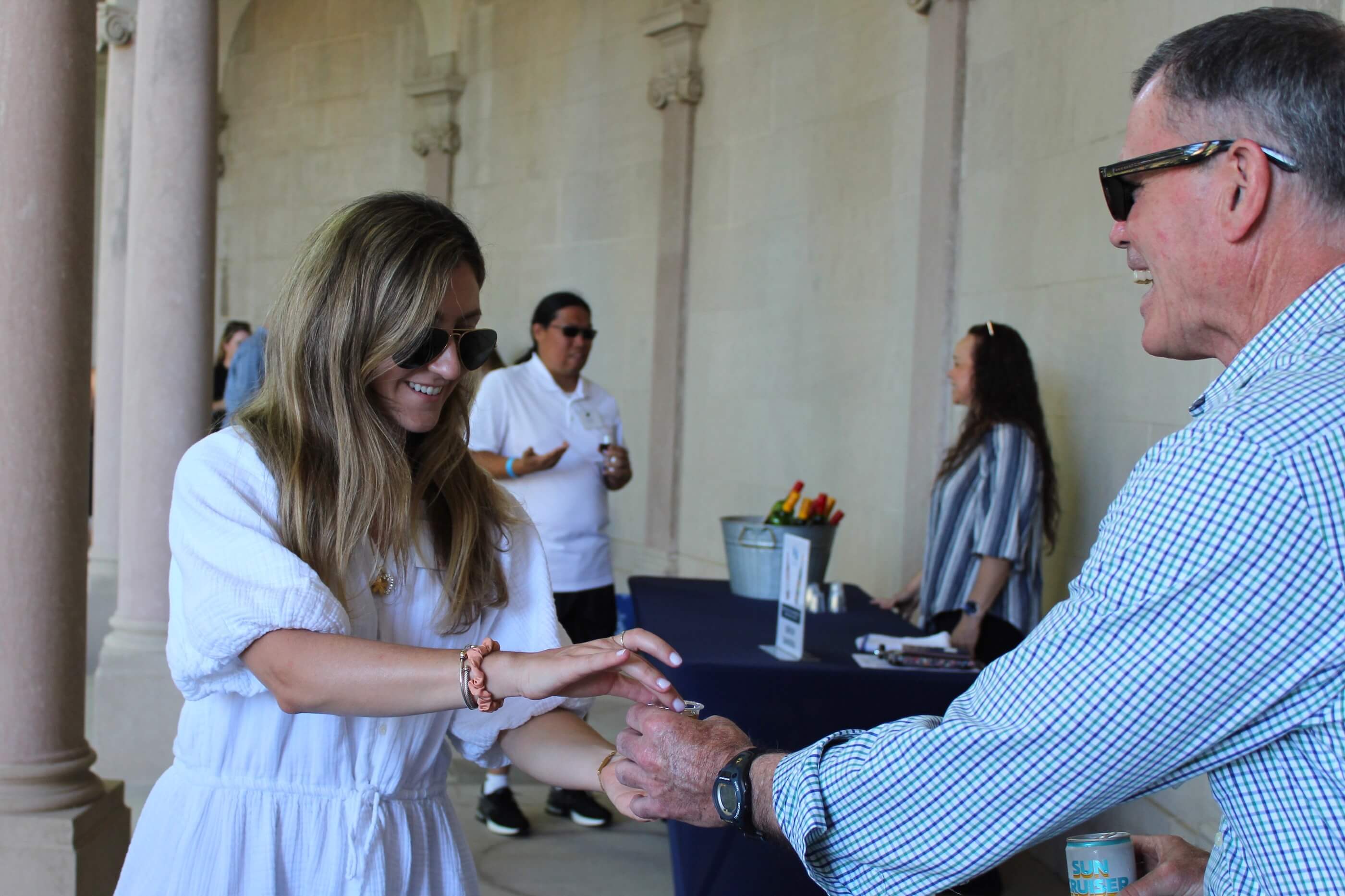 A volunteer hands back a tasting glass to a Wine vs Stein participants