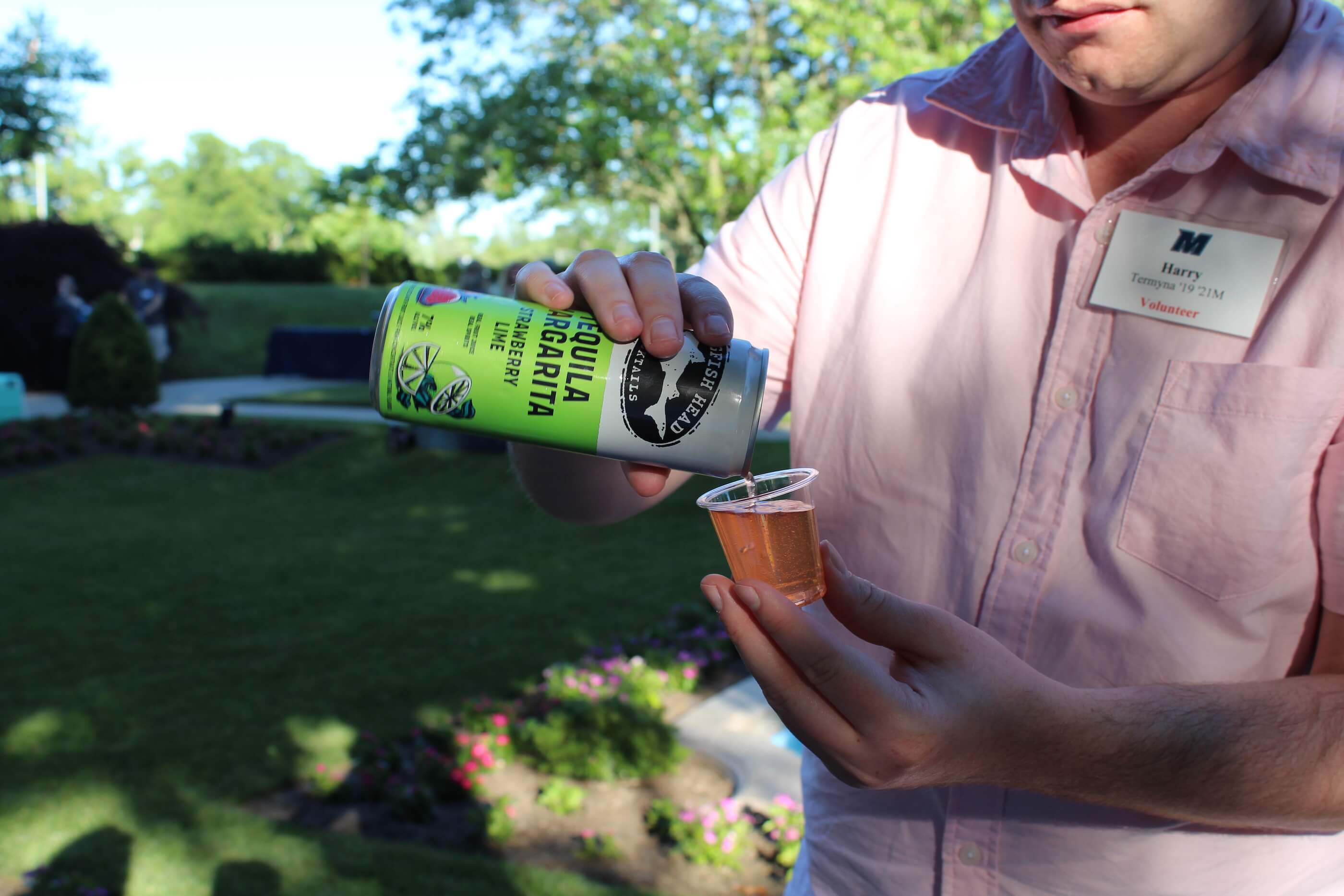 An event volunteer pores a tequila margarita from a can into a tasting glass