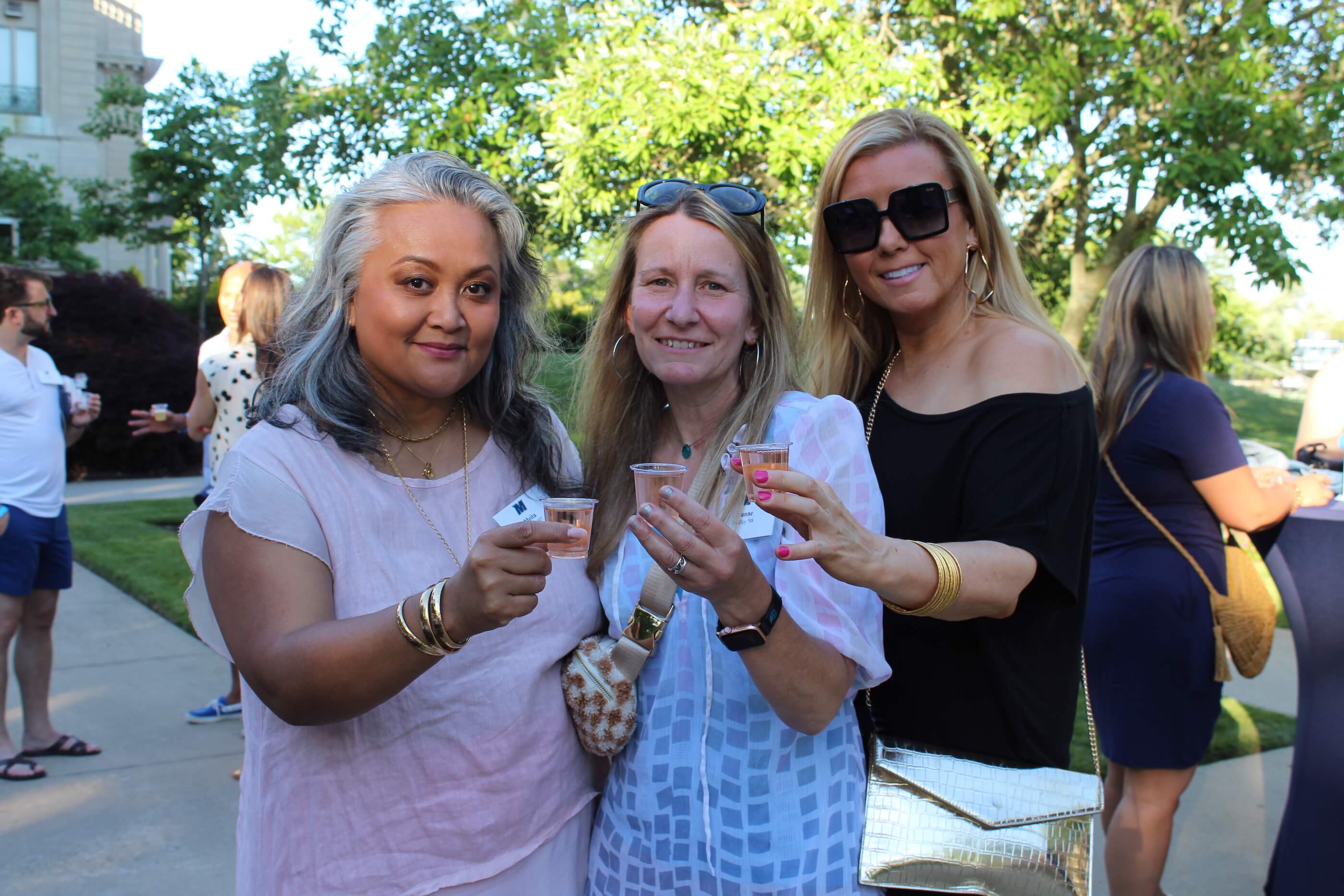 Three attendees holding their tasting glasses, each filled with a rosé