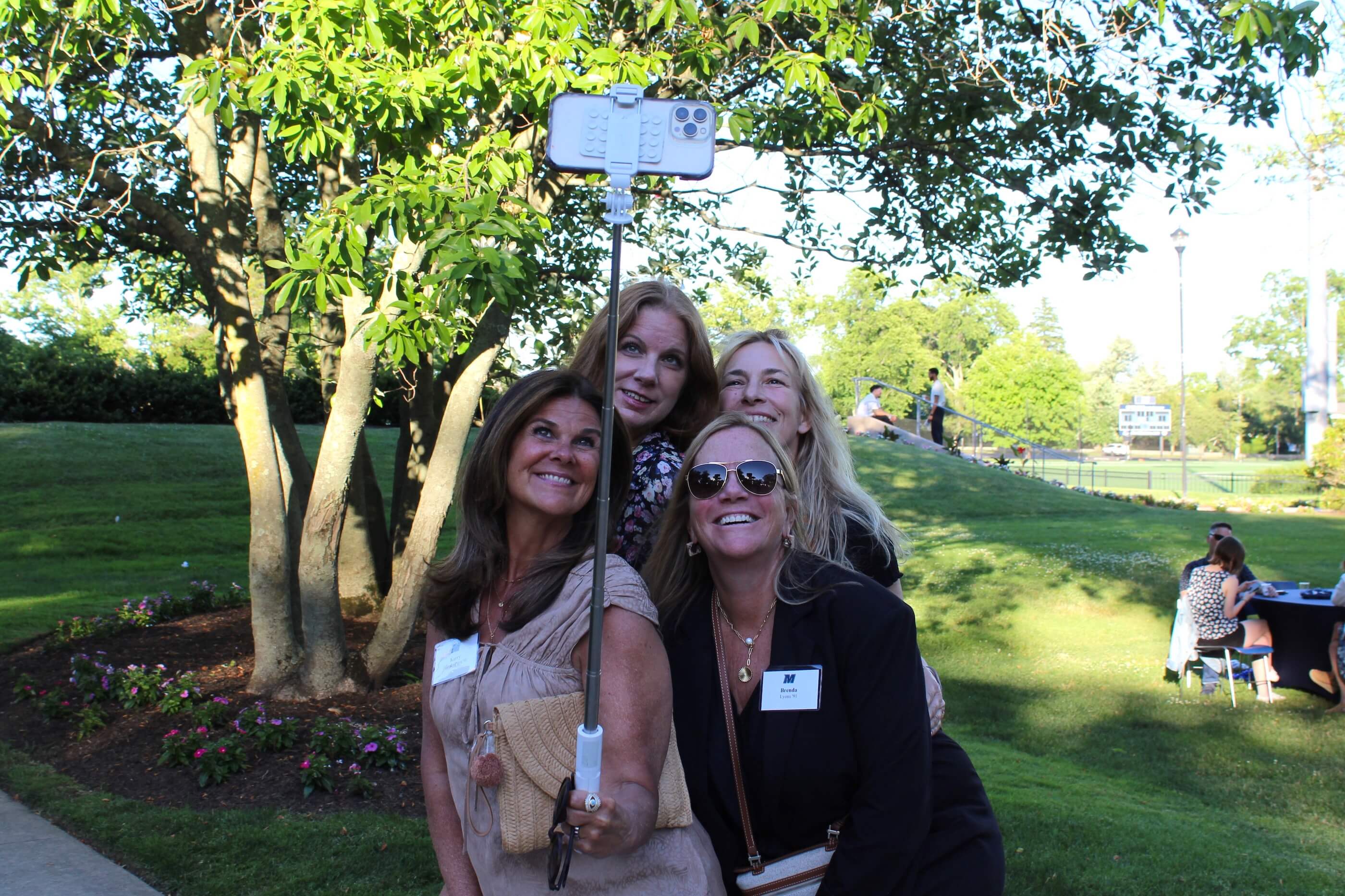 Four attendees taking a group selfie using a selfie stick