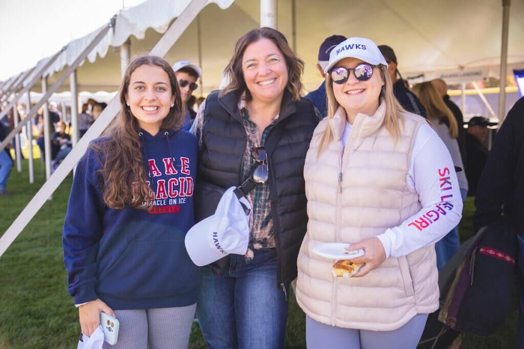 Three alumnae smile for camera outside ten