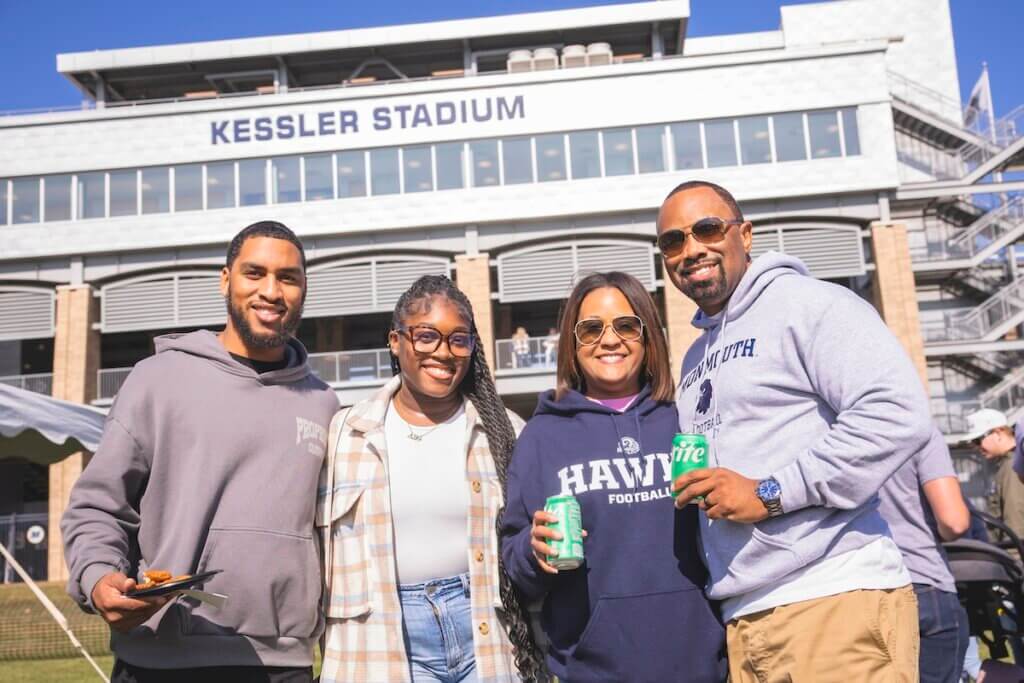 Four adults smile for camera in front of stadium