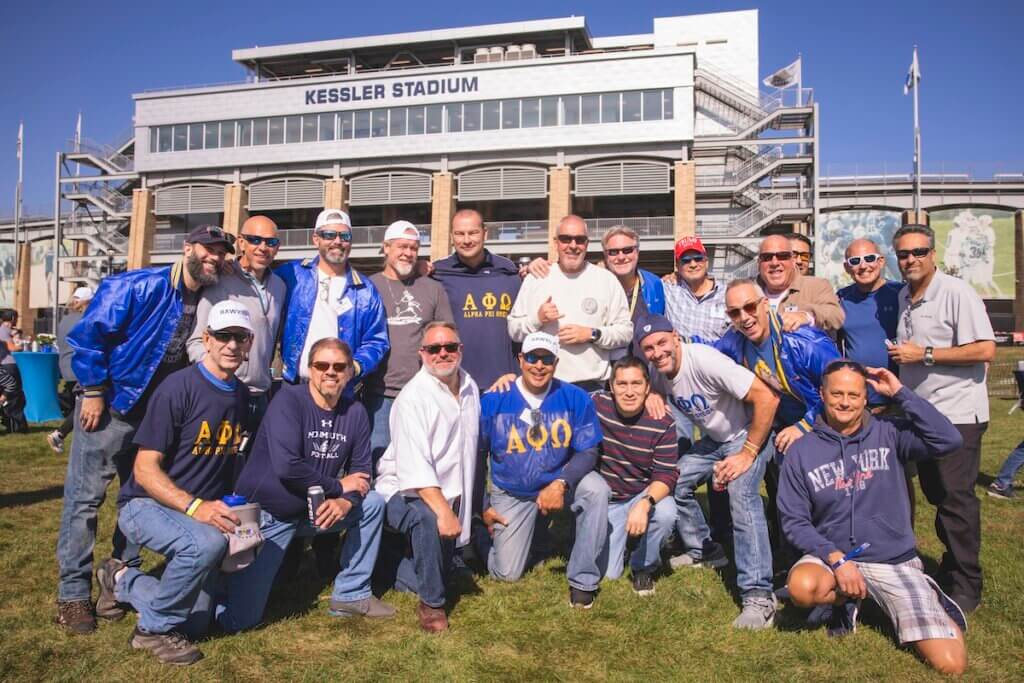 Around 20 APO fraternity members pose for photo outside stadium