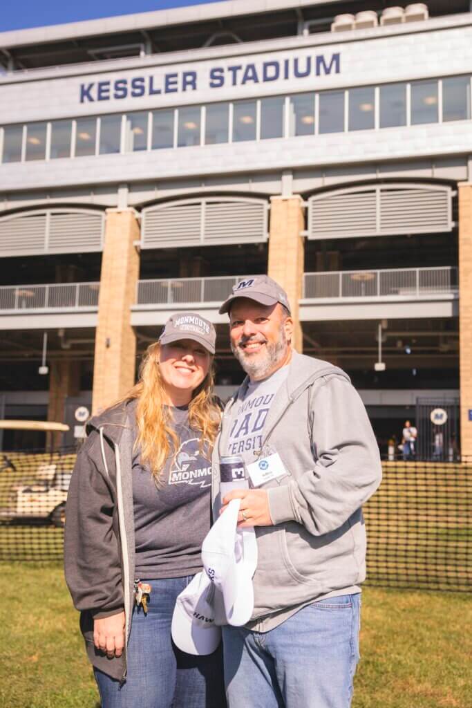 Man and woman posing for photo in front of stadium