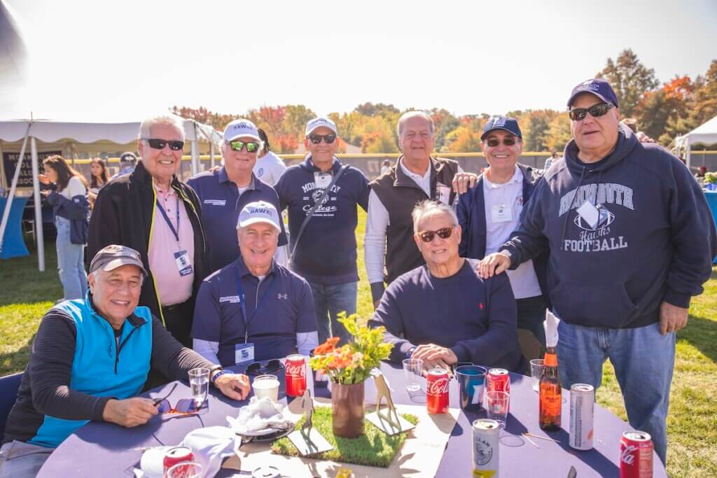 Alumni that graduated in the 1970s posing together by a table.