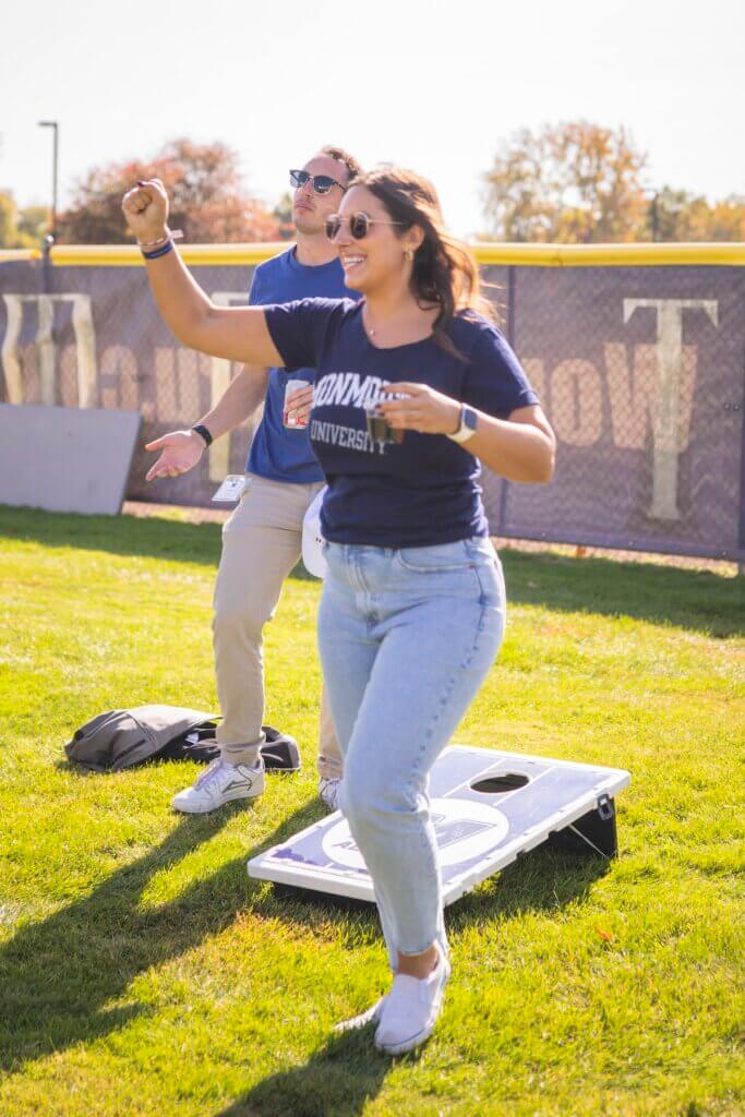 Two women playing corn hole on a lawn