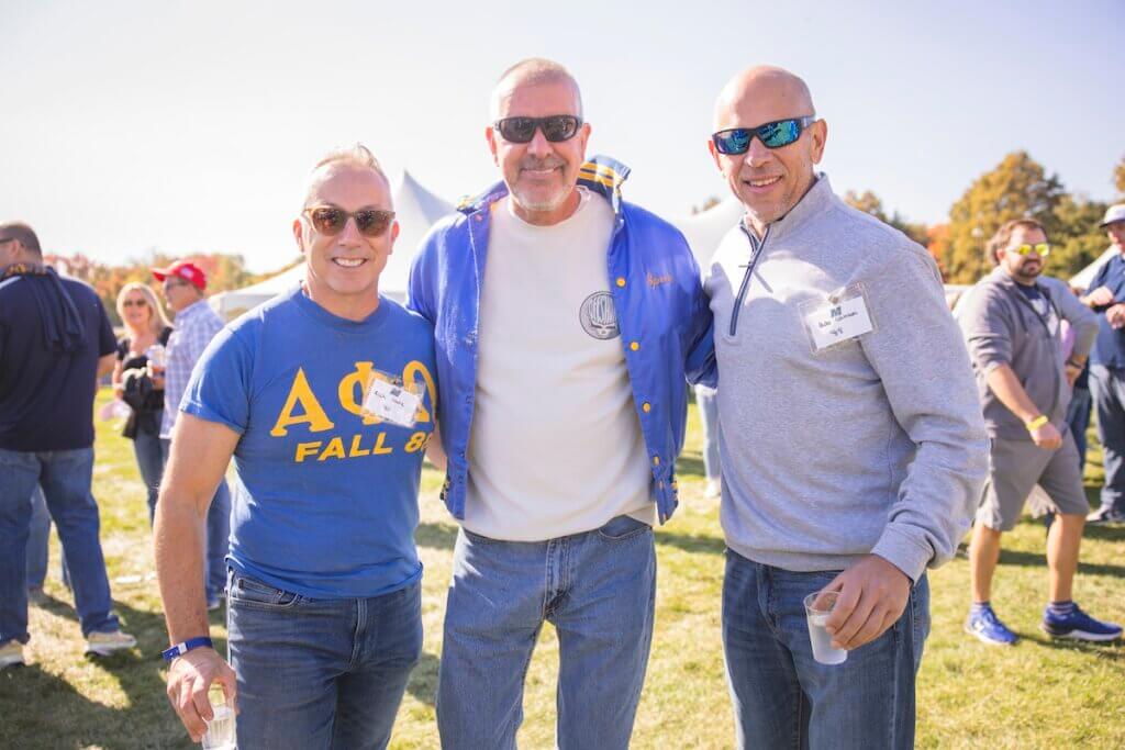 Men in fraternity gear and sunglasses smiling for camera