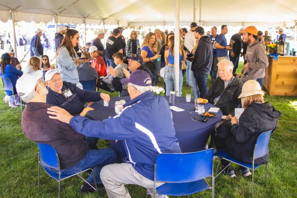 Group of men talking to each other at a table under a tent