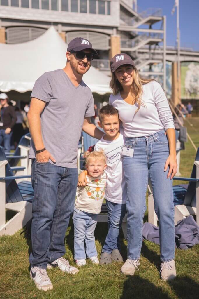 Parents and two young children posing for photo in front of stadium