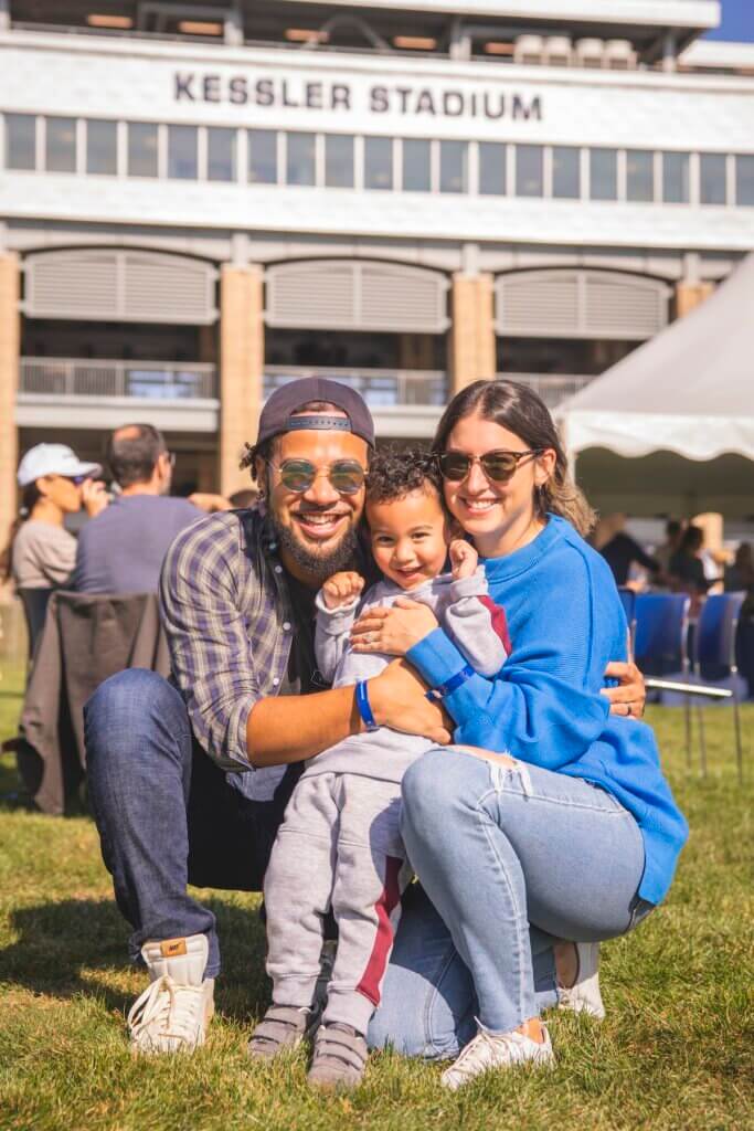 Two parents embrace their child in front of stadium