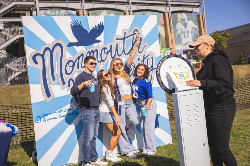 alumni posing for shot in front of mural