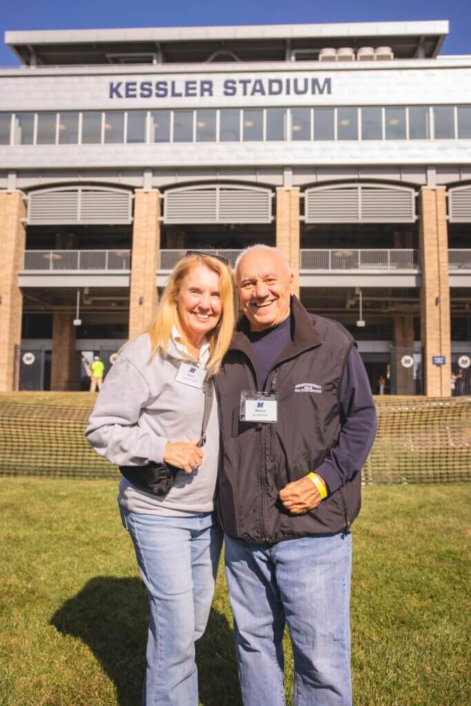 Man and woman posing for photo in front of football stadium