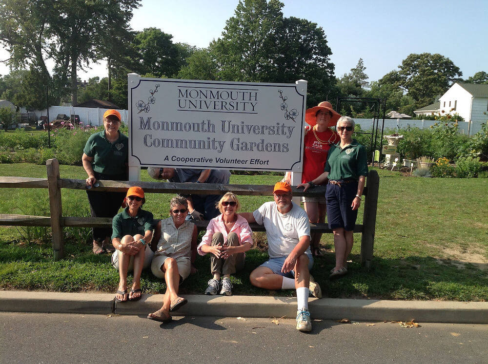 People posing for a shot in front of the Monmouth University Community Garden