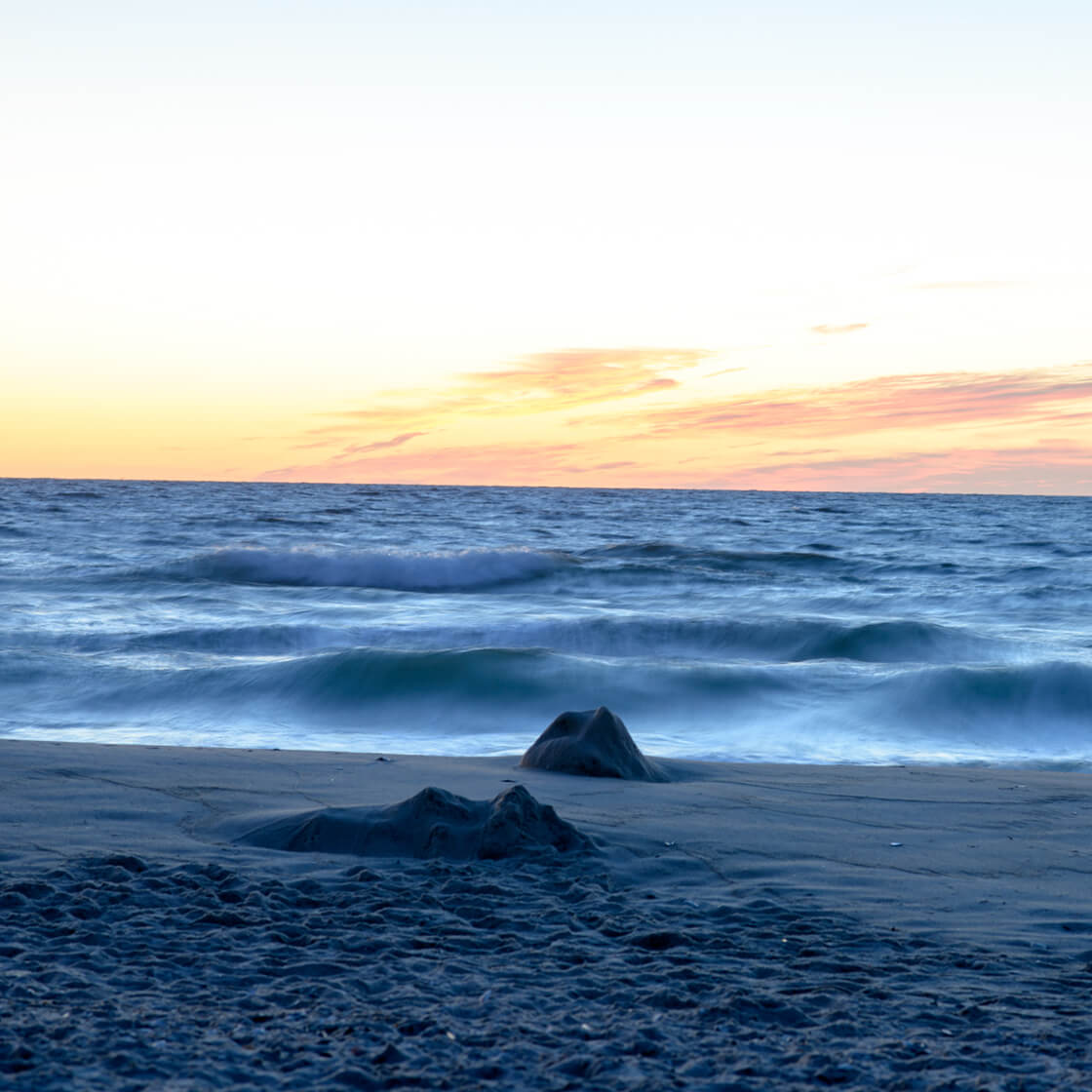 photo of a sunset, with mild waves crashing on a beach