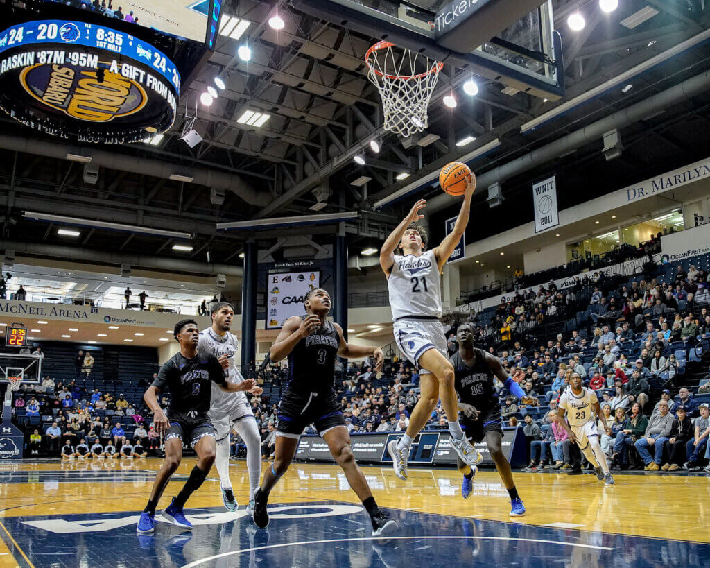 Basketball player performing a layup while his opponents look on