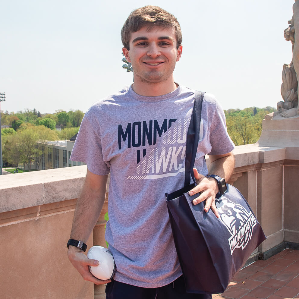A student holding and wearing Monmouth University swag