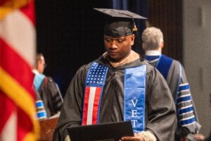 Student wearing commencement regalia and veteran stole.