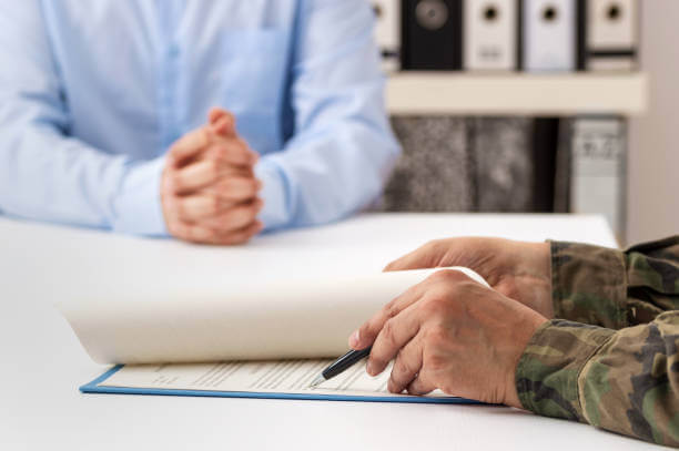 Hands of uniformed servicemember signing documents