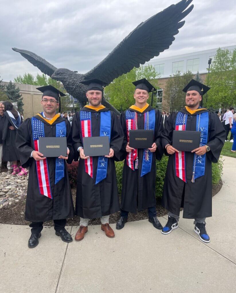 4 student veterans pictured at the hawk with their veteran stoles and holding their diplomas.