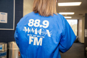 Woman wearing vintage blue jacket with 88.9 WMCX FM on back
