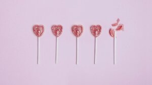Photograph of five heart-shaped lollypops, four of which are intact, and a fifth which is broken.