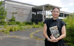Melissa Ziobro stands outside abandoned building at Fort Monmouth holding her book about the history of the Fort. Photo: Thomas P. Costello/Asbury Park Press