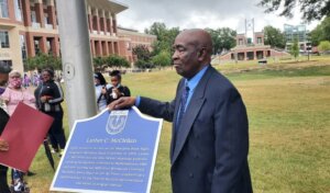 Luther C. McClellan stands near marker in his honor