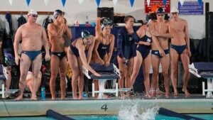 Members of the Monmouth University swim team cheering on their teammate in the water