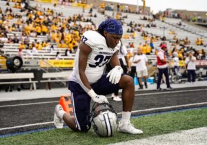 Kadeem McKnight kneels at sidelines of football game