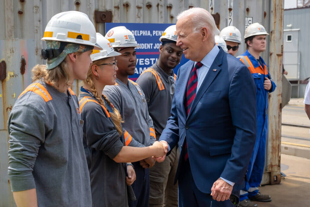 Image of President Biden shaking hands with factory workers.