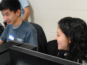 1 male student and 1 female student smiling and having fun at the programming competition