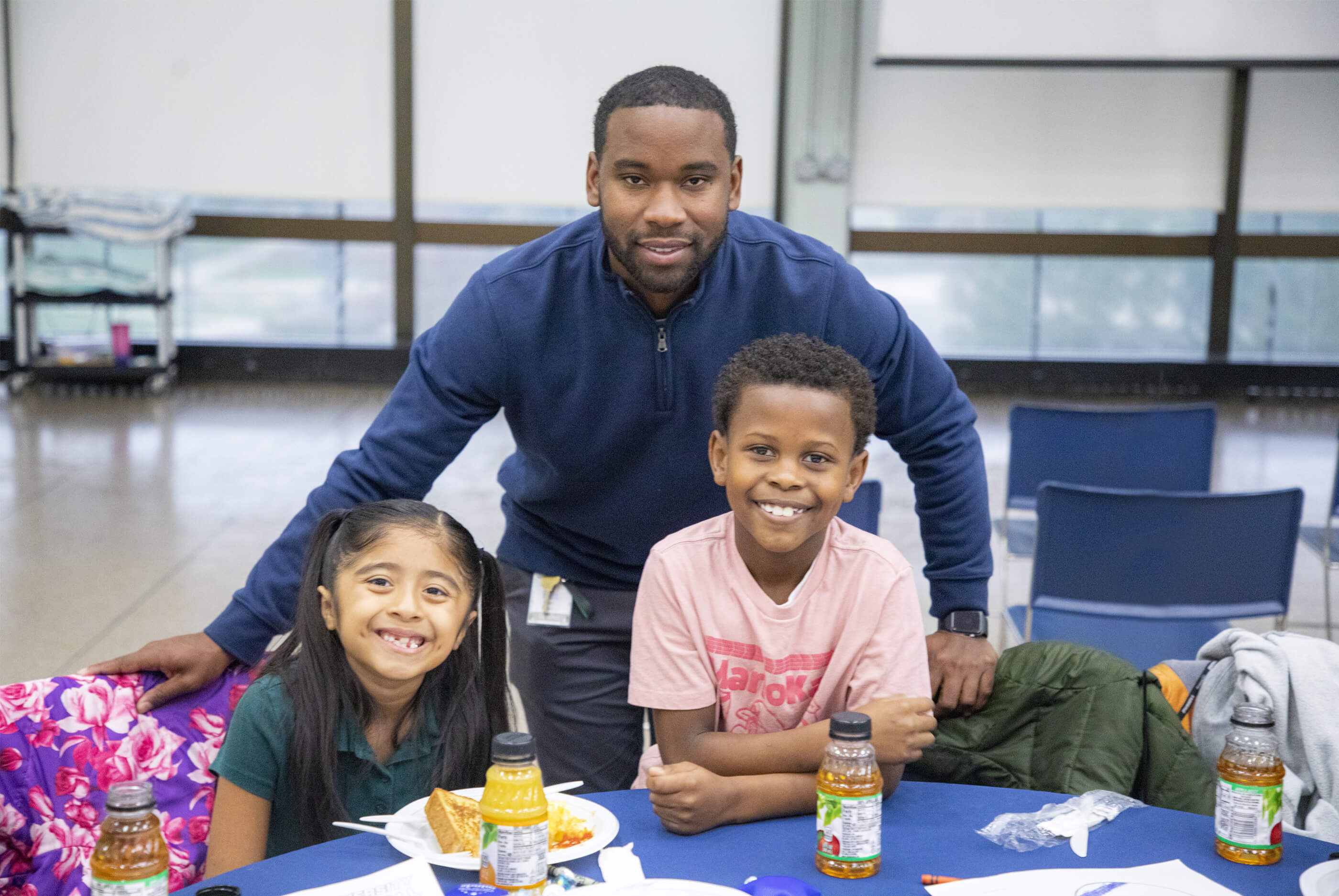 Professional at table with two children, all smiling for the camera