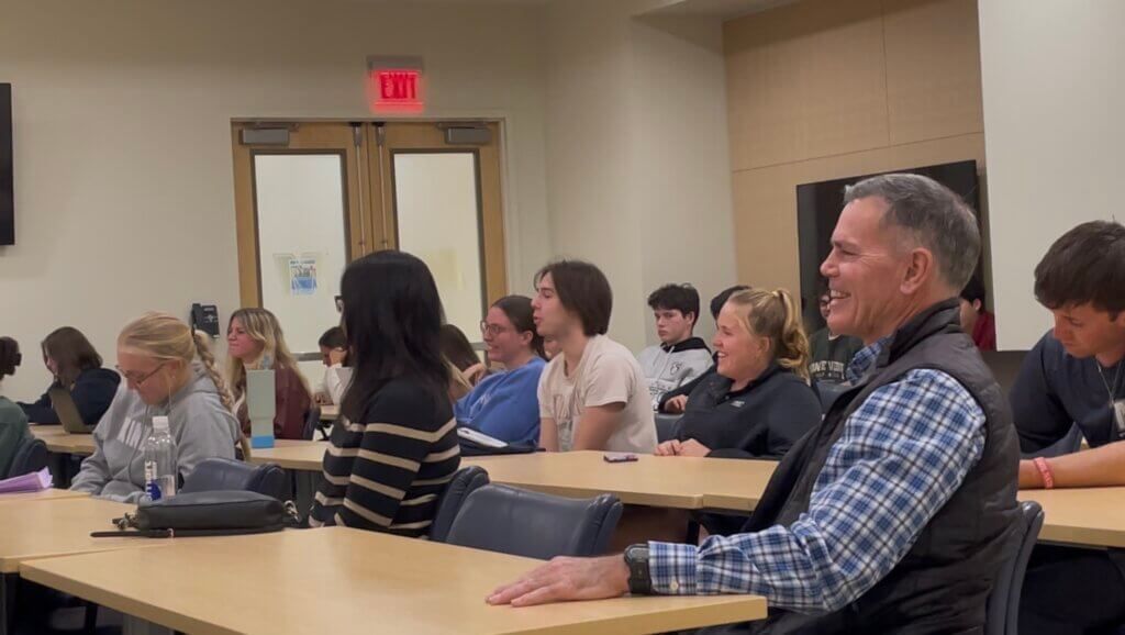 Young adults and older adults listen at desks in a classroom