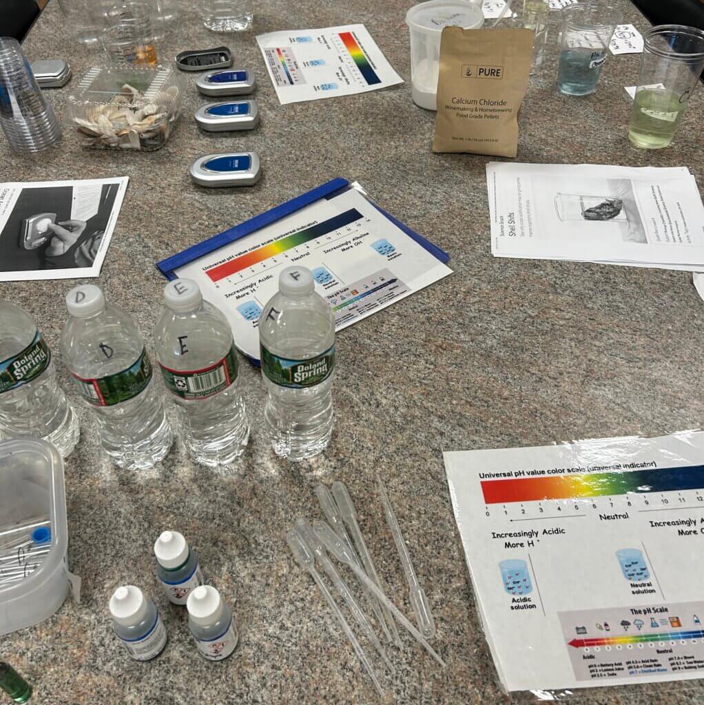 A table with bottles of Poland Spring water and scientific equipment. Includes documents on water acidity.